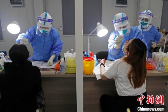 机场海关工作人员对旅客进行核酸检测。　殷立勤 摄