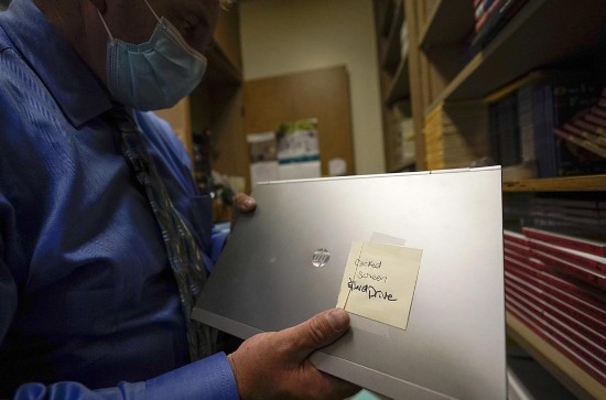 汤姆·鲍姆加顿手持损坏的笔记本电脑(图片来源:美联社)