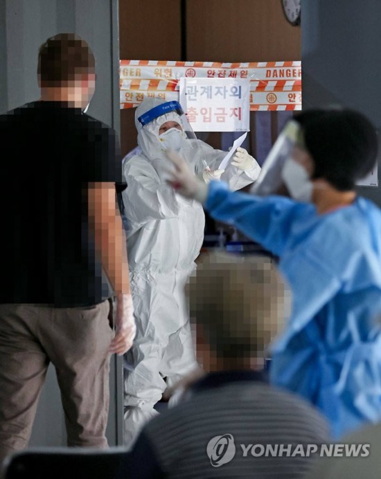 31日上午,首尔城东区保健所内的新冠病毒筛查诊所中,医务人员正在引导当地市民排队接受检查。