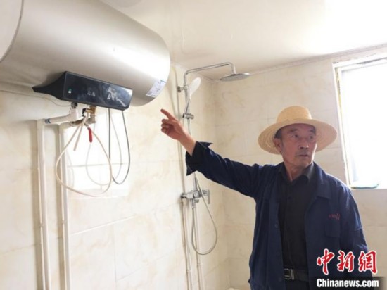 图为刘向信展示自家安装的热水器。　张婧 摄