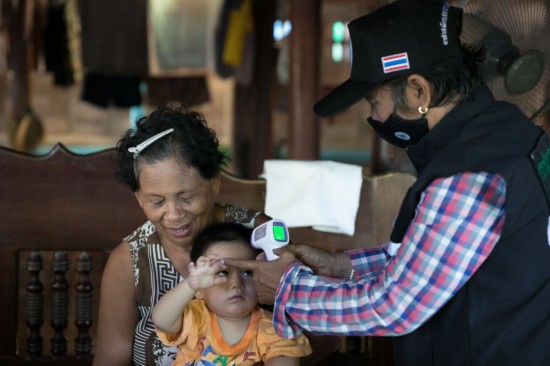 6月24日，泰国西部叻武里府邦沛县的乡村医疗志愿者瑙瓦拉（右）为一名儿童测量体温。 新华社记者 张可任摄