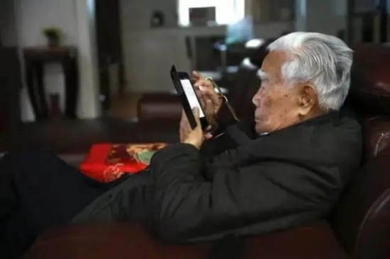 97岁的张世英依然思维活跃、与时俱进。图为他在智能手机上浏览文章。赵凤兰摄