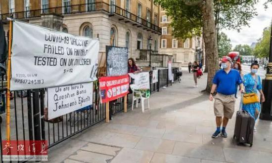  ▲资料图片：人们从反疫苗抗议者打出的标语前走过。（英国《卫报》网站）