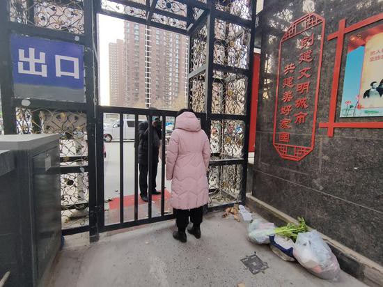 2021年1月6日,河北省石家庄市,石家庄对全市所有社区、农村实行闭环管控,全面启动全员核酸检测。图为石家庄市天滋嘉鲤北区实行闭环管理,小区居民隔铁门取外卖蔬菜。图源IC