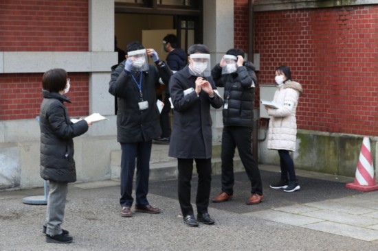 佩戴透明面罩的考场工作人员(时事通信社)