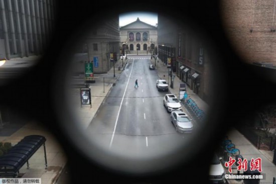 图为2020年3月23日在美国伊利诺伊州,一名男子走过芝加哥艺术学院附近一条几乎空无一人的亚当斯街。