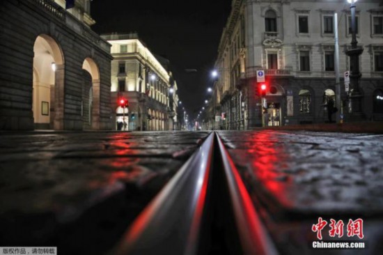 资料图：意大利北部米兰，斯卡拉歌剧院前的一条空街被红灯照亮。该国已采取一系列新措施，进一步加强疫情防控。