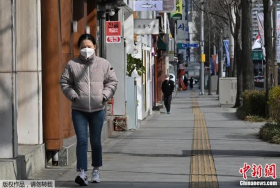 2020年2月27日，一名女子戴着口罩走在韩国大邱街道上。