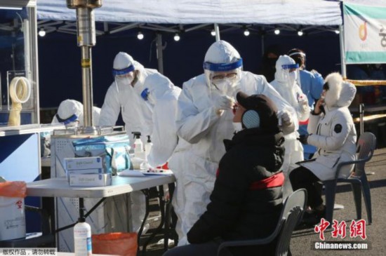 当地时间2020年12月14日，韩国首尔，医务人员对一名市民进行新冠病毒检测。