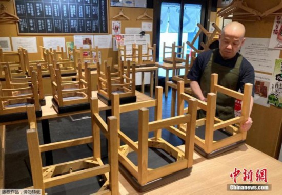 资料图：2021年1月8日，日本东京，一位餐厅老板正在收拾店内的座椅，准备关店。