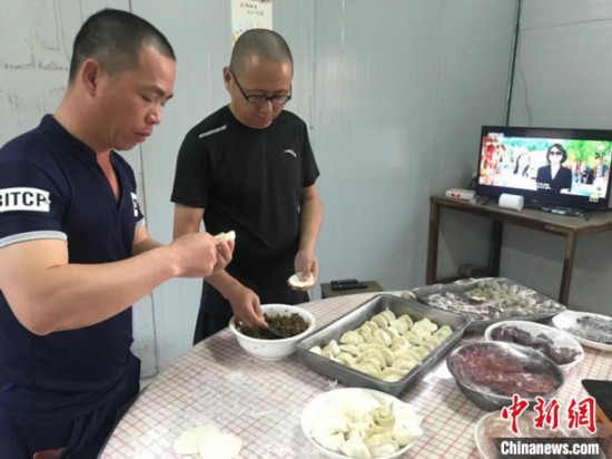 图为项目部员工包饺子 许明亮 摄