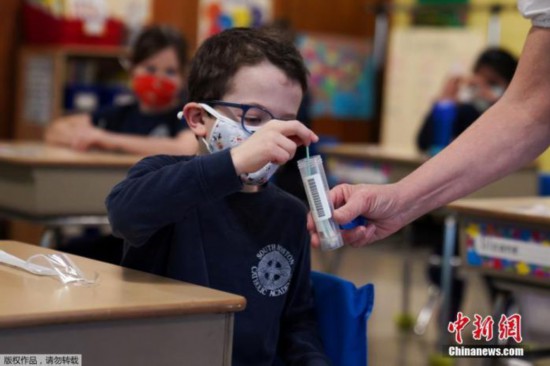 当时间1月27日，美国马萨诸塞州波士顿市一所学校内，小学生们佩戴口罩在教室学习。在此期间，学校老师要求孩子各自进行核酸检测，孩子们把做完鼻拭的棉签交给老师。