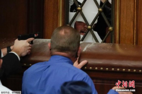 资料图：当地时间1月6日，美国国会参众两院召开联席会议期间，特朗普支持者闯入国会大厦引发骚乱，在众议院内警察隔着门窗持枪与抗议者对峙。