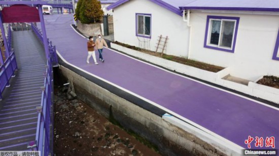 游客走过紫色的街道。