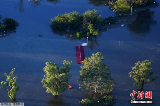 当地时间3月24日，澳大利亚悉尼附近的温莎地区，航拍画面显示洪水几乎淹没房屋，隐约能看到些许房屋屋顶在水面之上。