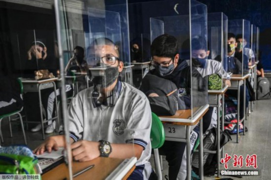 资料图：当地时间2月25日，哥伦比亚Itagui一所学校，为防范疫情，学生们戴口罩在设置的挡板里听课学习。