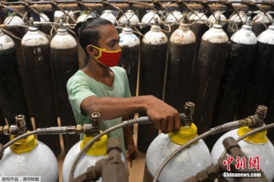 当地时间4月24日,印度新增确诊病例再创新高,连续第3天超过30万例。印度疫情蔓延导致多地医院出现供氧危机,许多医务人员、工作人员和普通民众都带着氧气瓶到氧气加气站。图为一名工人在钦奈郊区的一个设施中填充了医用氧气瓶。