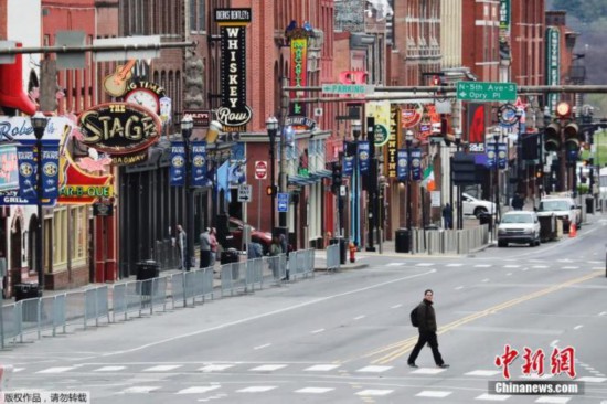 资料图：新冠疫情下的美国。图为在美国田纳西州纳什维尔，一个男人走过冷清的百老汇大街。