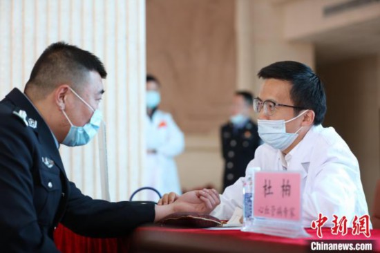 图为义诊专家组成员、中国中医科学院副主任医师杜柏为西藏出入境边防检查总站民警诊断身体。　何宇恒 摄