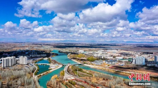 资料图:航拍春雨后的新疆博湖县城,蓝天、白云、碧水与河边芦苇交相辉映。年磊 摄