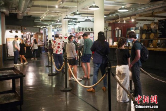 当地时间5月25日，顾客在美国纽约切尔西市场一家餐厅排队购买餐食。