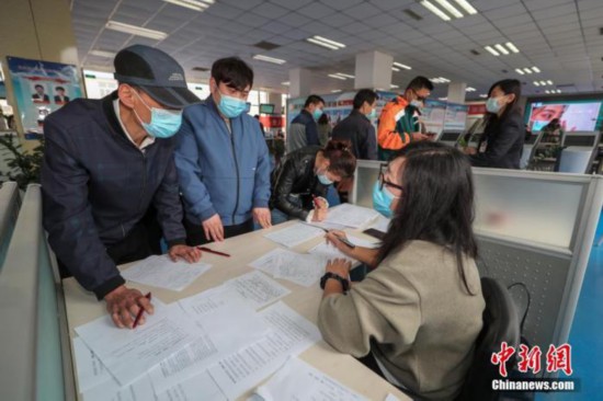 资料图：4月2日，北京市顺义区人力资源市场内，求职者(左)与用工企业交谈。 中新社记者 贾天勇 摄