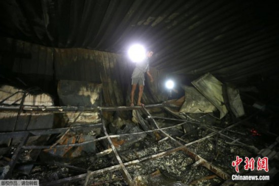 2021年7月13日，一名男子在伊拉克纳西里耶一间收治新冠患者的医院检查起火现场的损坏情况。