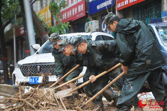 官兵正在河南巩义米河镇街道上清理杂物。