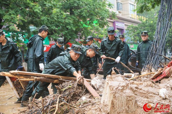 官兵正在河南巩义米河镇街道上清理杂物。