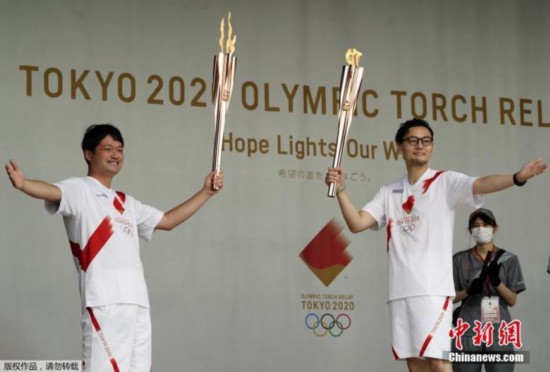 资料图：当地时间7月9日，东京奥运会圣火抵达日本东京都，圣火迎接仪式在驹泽奥林匹克公园体育场举行。图为火炬手们展示奥运圣火。