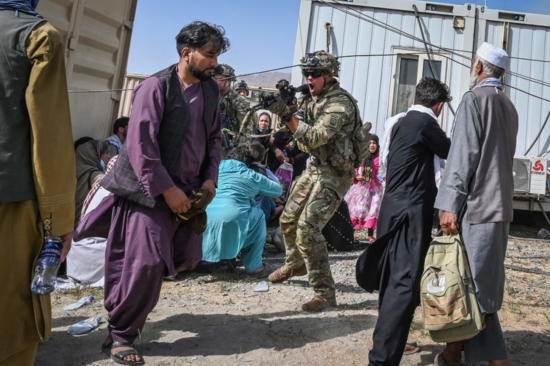 8月16日，在阿富汗喀布尔机场，一名美军士兵用枪指向一名阿富汗男子。新华社/法新