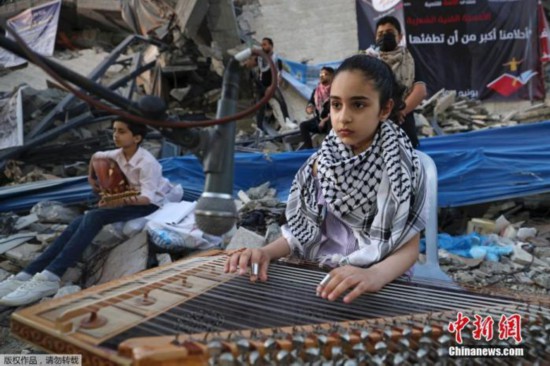 资料图：当地时间6月2日，加沙地带，巴勒斯坦音乐家在遭受以色列空袭的房屋废墟上演奏音乐。