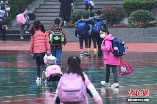 资料图：11月17日，重庆渝北回兴小学校大门处，学生们戴着口罩有序进入校园复学。陈超 摄