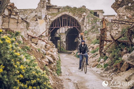 叙利亚北部城市阿勒颇，一名男子骑车从被战争损毁的古老市场里经过。2016年年底，叙政府军从反对派手中完全收复阿勒颇。人民网记者 薛丹摄