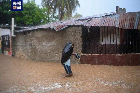 当地时间6月3日，海地当地居民涉水穿过被淹的道路。