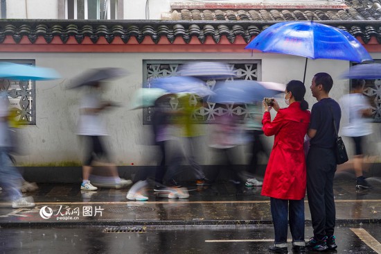 6月7日，在浙江省2023年普通高校招生考试镇海中学考点，家长冒雨目送子女进入考场。人民网 章勇涛摄