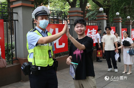 6月7日8时许，武汉中学考点门口，交警在维护秩序，并祝考生金榜题名。人民网记者 肖璐欣摄