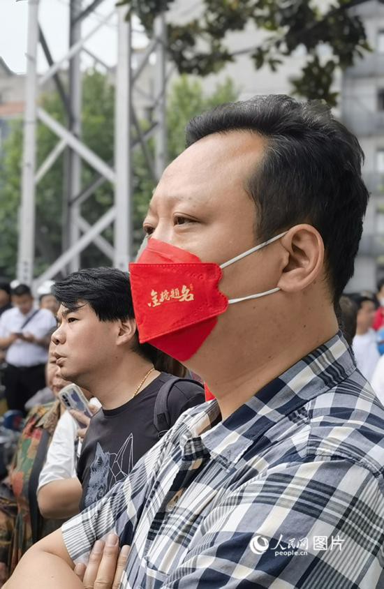 6月7日早，在武汉市第二十六中学考点外，送考家长戴着印有“金榜题名”的口罩。人民网 周雯摄