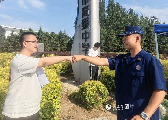 6月7日，辽宁营口老边区消防救援大队的消防员为高考学子加油助威。人民网记者 尹柏寒摄