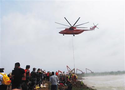8月14日,寿光市北部张僧河决堤现场,救援直升机正在将装有砂石的重型袋投入决口。图/视觉中国
