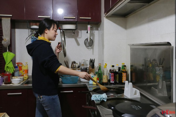 ▲ 薛春艳用锅盖挡脸，以免被热油溅到。