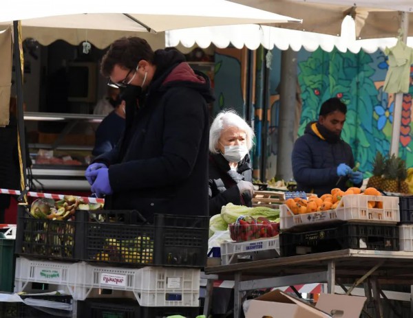  在意大利首都罗马，人们戴着口罩在市场购买蔬果。