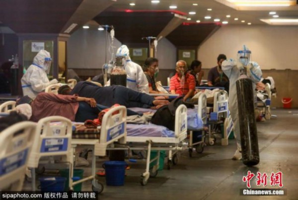 资料图:连续激增的确诊病例,导致印度多地医疗系统瘫痪,许多患者只能在临时搭建的场所接受治疗。图为医护人员在运送氧气罐。