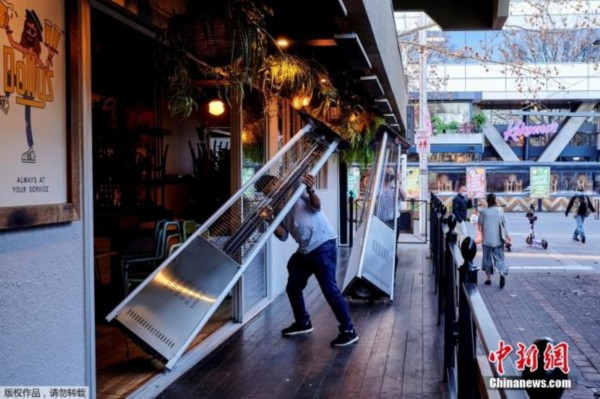 资料图：澳大利亚首都堪培拉，酒吧的工作人员正在将户外设施收回店内。