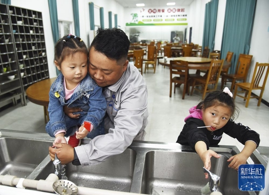 &uarr;从施工现场回来，杨兴义在食堂为小女儿洗手（1月24日摄）。新华社记者田建川摄