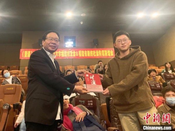 图为复旦大学福建校友会副会长叶道明(左)向观影者赠书。　朱婷 摄