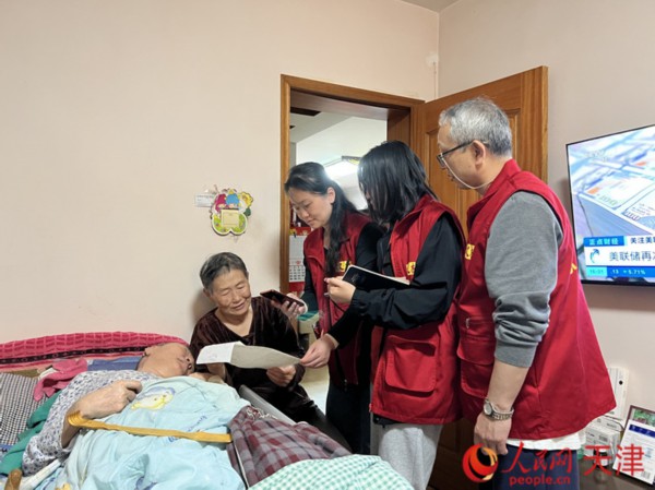 津南区双林街林城佳苑社区工作人员用手机上传病例照片,帮助孟大娘完成长护险报销流程。人民网记者 孙翼飞摄