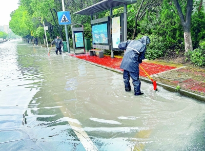 6月19日早晨的大雨造成雨花台区雄风路出现短时积水,板桥街道综合行政执法局的防汛人员及时清理雨水箅、疏通排水管网。 南京日报/紫金山新闻记者 段仁虎 通讯员 刘瑾璇 摄