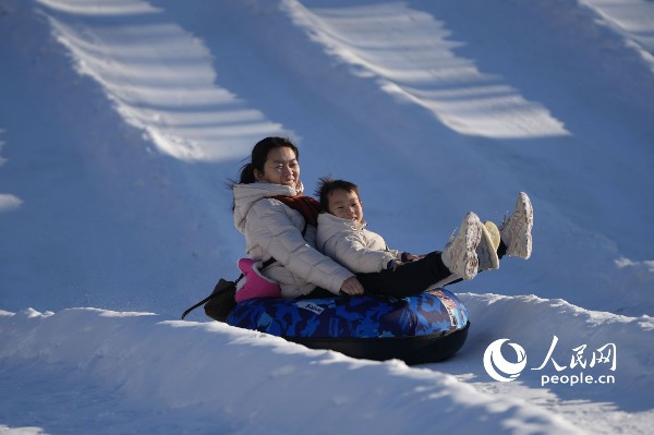 在北京市一大型游乐场里举办的“冰雪节”上,游客正在体验冰雪游乐项目。人民网记者 王天乐摄