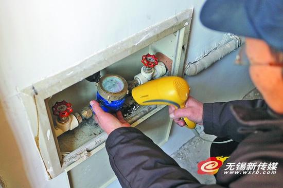 昨天，一居民用电吹风加热被冻住的水表和水管。（卢易　摄）